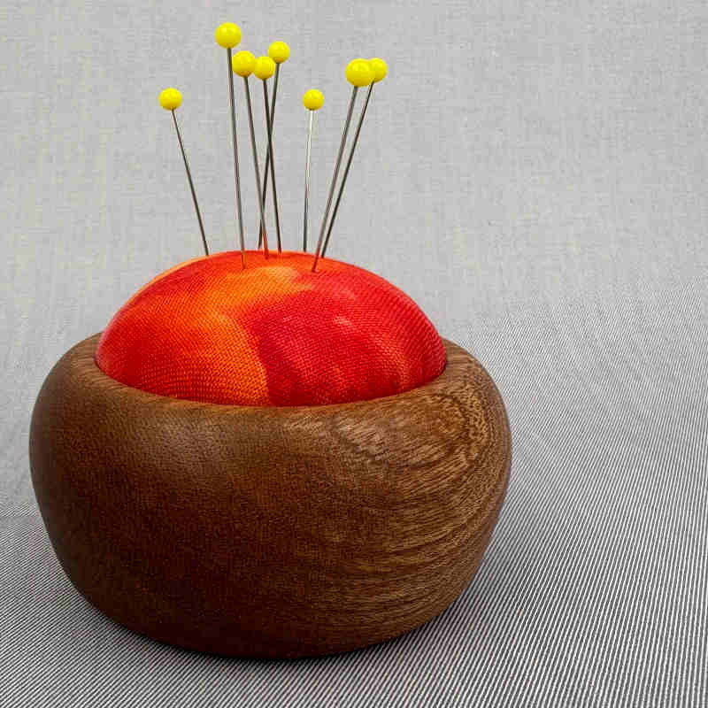 træbase til nålepude med rødt stof og knappenåle