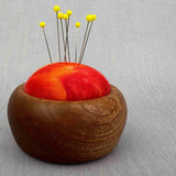 træbase til nålepude med rødt stof og knappenåle